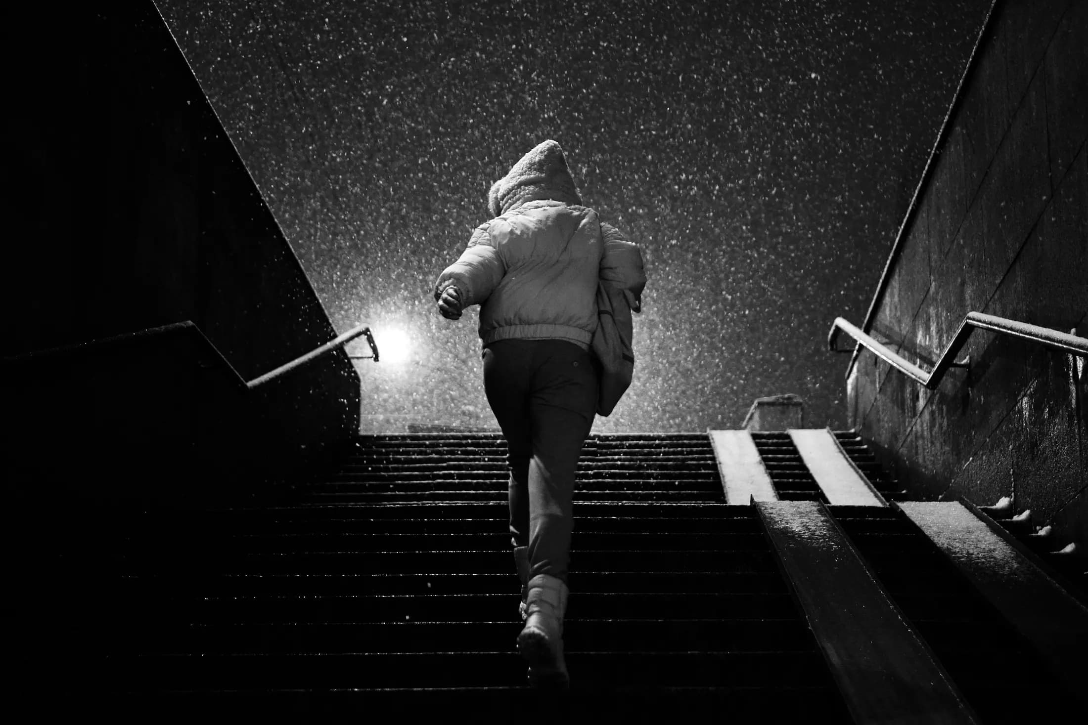 Coureur montant un escalier sous la neige, sac sur le dos